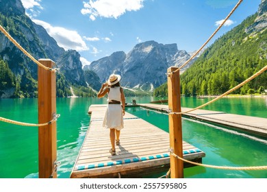 Woman walking along a wooden pier at lake braies, enjoying the turquoise waters and stunning mountain landscape of the dolomites on a sunny summer day - Powered by Shutterstock