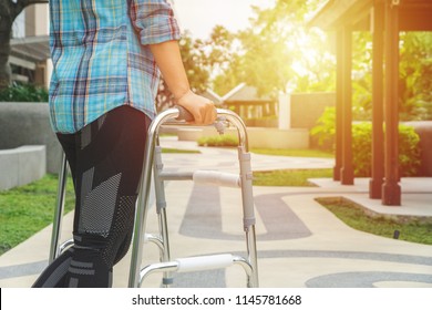 Woman walking with an aluminum walker at a park. Image with copy space for text or design