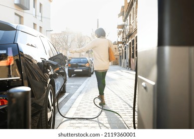 Woman Walking Away After Plug The Electric Car To The City Charging Station.