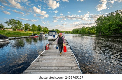 Woman walking away from camera on boat dock carrying items - Powered by Shutterstock