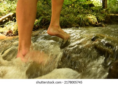 A woman walking barefoot in a clean flowing stream during a sunny day - Shutterstock ID 2178005745