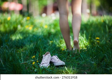 Woman Walking Barefoot On The Grass, Pink Shoes In Focus, Shallow DOF