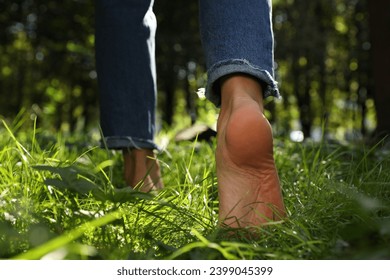 Woman walking barefoot on green grass in park, closeup - Powered by Shutterstock