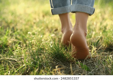 Woman walking barefoot on green grass outdoors, closeup. Space for text - Powered by Shutterstock