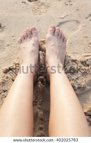 Woman walking barefoot on sunny beach in summer day