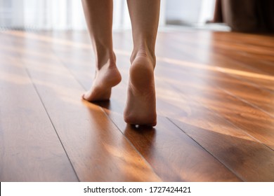 Woman walking barefoot on toes at warm laminate floor close up rear view. Sunny light bedroom good morning welcome new day, modern comfy apartments with under floor heating system, footcare concept - Shutterstock ID 1727424421