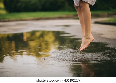 Woman Walking Barefoot Through Puddle Outdoors