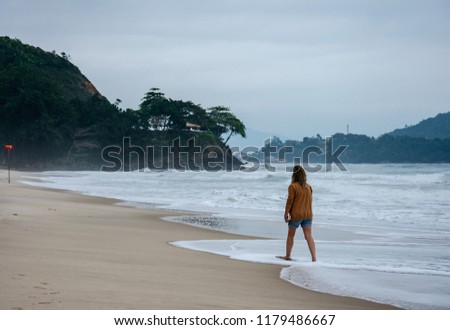 A woman walking at Toninhas’ beach in Ubatuba, Sao Paulo, Brazil