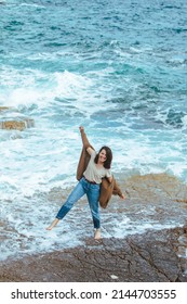 Woman Walking By Rocky Beach In Wet Jeans Barefoot. Summer Sea Vacation