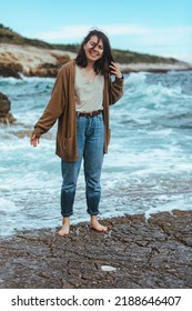 Woman Walking By Rocky Beach In Wet Jeans Barefoot. Summer Sea Vacation