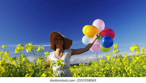 Woman walking with colorful balloons in mustard field on a sunny day - Powered by Shutterstock