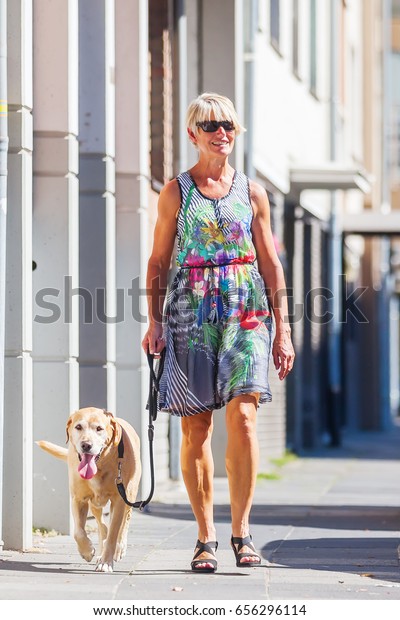 woman walking\
with a dog at the leash in the\
city