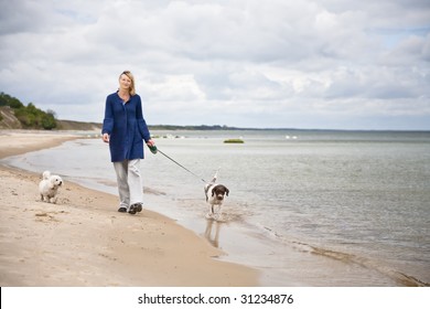 Woman Walking The Dog On The Beach