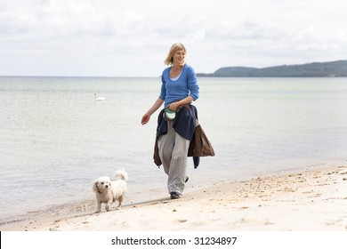 Woman Walking The Dog On The Beach