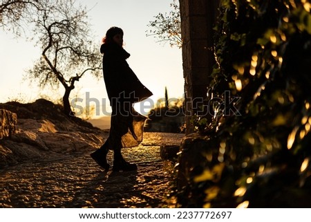 woman walking down the street of an old town at sunset backlit ,selective focus, blur, blurred