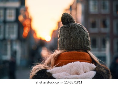 Woman walking down the streets of Amsterdam wearing a hat
