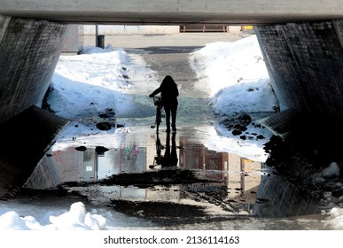 A Woman Walking Her Bicycle Through The Wet Underway