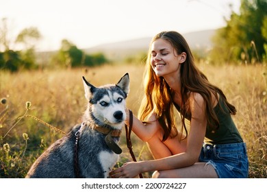 Woman Walking Her Husky Dog And Smiling Happily With Teeth On A Nature Walk On The Grass In The Autumn Sunset, Lifestyle Dog Friend