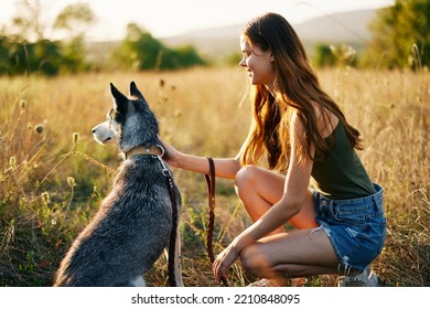 Woman Walking Her Husky Dog And Smiling Happily With Teeth On A Nature Walk On The Grass In The Autumn Sunset, Lifestyle Dog Friend