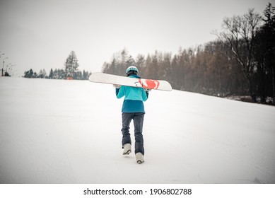 Woman walking up the hill to learn snowboarding
