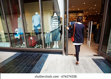 Woman Walking Into A Garment Store With Mannequins 