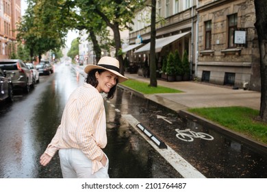 Woman Walking In The Middle Of The Street. Happy Female In Summer Rain. City Lifestyle Fashion. Woman Wearing Summer Clothes And Hat