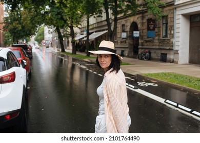 Woman Walking In The Middle Of The Street. Happy Female In Summer Rain. City Lifestyle Fashion. Woman Wearing Summer Clothes And Hat