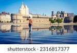 Woman walking in mirror water in Nantes- Loire-Atlantique,  Pays de la Loire in France- Castle of the Dukes of Brittany