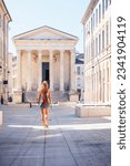 Woman walking in Nimes city street- Temple Maison carrée- France