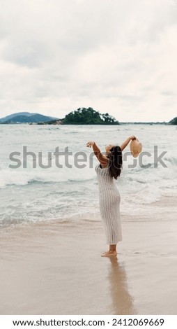 Woman walking in ocean water waves on sandy beach, Female tourist on summer travel vacation, Slow motion, vertical shot
