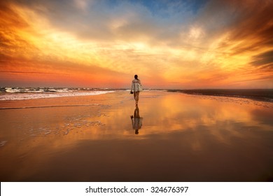woman walking on the beach near the ocean at the sunset