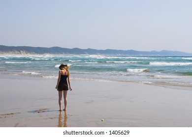 A Woman Walking On The Beach, Picking Up Shells