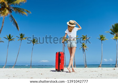 woman walking on the beach with a red suitcase rest nature travel fun model
