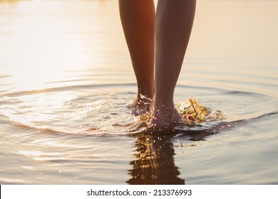 Woman walking on the beach at sunset