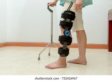 Woman Walking On Crutches, Wearing Knee Support In Rehab Center