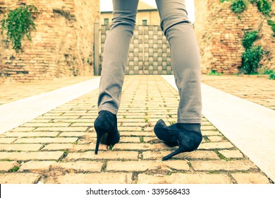 Woman walking on high heeled shoes - Closeup of young girl legs with twisted ankle - Slim teenager wearing trendy tight jeans pants - Concept of youth fashion and social problems related to anorexia
