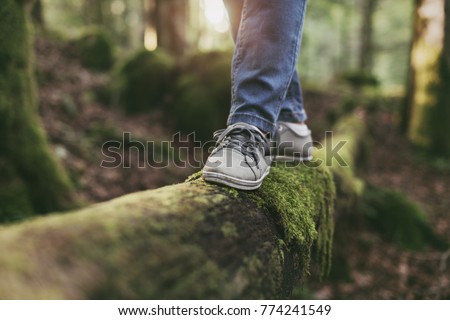Woman walking on a log in the forest and balancing: physical exercise, healthy lifestyle and harmony concept