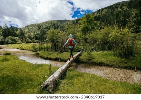 Woman walking on a one plank bridge in high altitude mountains