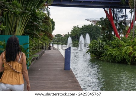 Woman walking on path close to river  with fountains in park 