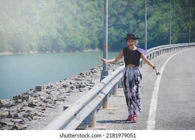 Woman Walking On The Road Side Of A Dam In Kanchanaburi, Thailand.