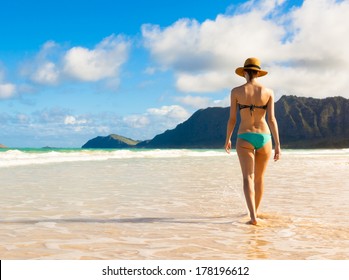 Woman walking on sand beach in Hawaii. Beach travel.