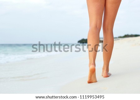 Woman walking on sand beach leaving footprints in the sand. Сlose up of woman leg on the beach.Feet female 