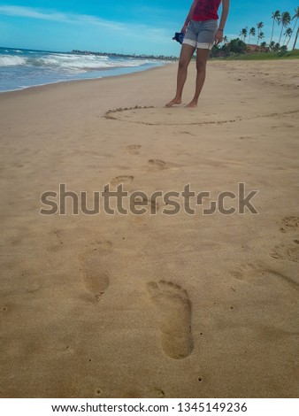 Woman walking on sand beach leaving footprints in the sand. Closeup detail of female feet at Brazil.
