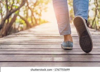 Woman is walking on small wood bridge to nature walk way with sunlight flare background. - Shutterstock ID 1767755699