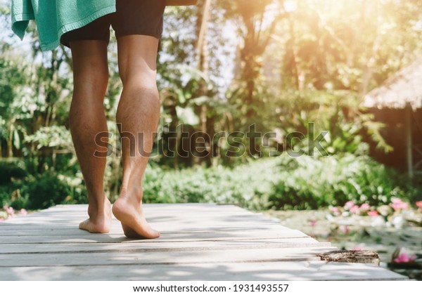 Woman is walking on small wood bridge\
to nature walk way with sunlight flare\
background.