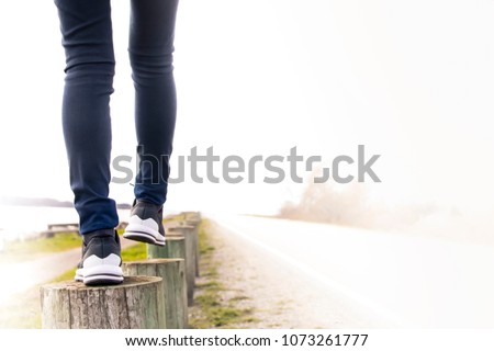 A woman walking on stump carefully next to the road. Concept of living life with confidence and take care every steps of moving forward to make sure life safe. Free copied space for text on right.