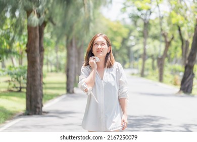 Woman walking in the park having sunstroke in summer hot weather, Young pretty girl drying sweat using a wipe on a warm summer day in a park - Shutterstock ID 2167250079
