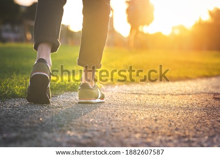 Woman walking in the park, outdoors. Closeup on shoe with rolled up jeans. Taking a step. New life concept