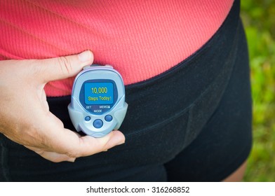 A Woman Walking With A Pedometer Reaching Her Goal Of 10,000 Steps For The Day