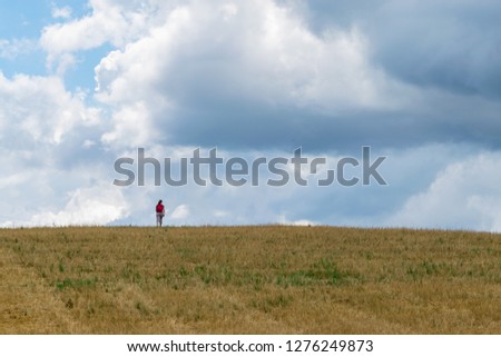 A woman walking in a plantation field on an amazing agricultural landscape with a dramatic sky near Curitiba, Parana, Brazil.